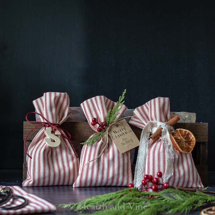 Three gift bags with red and white striped bags in front of a wood box