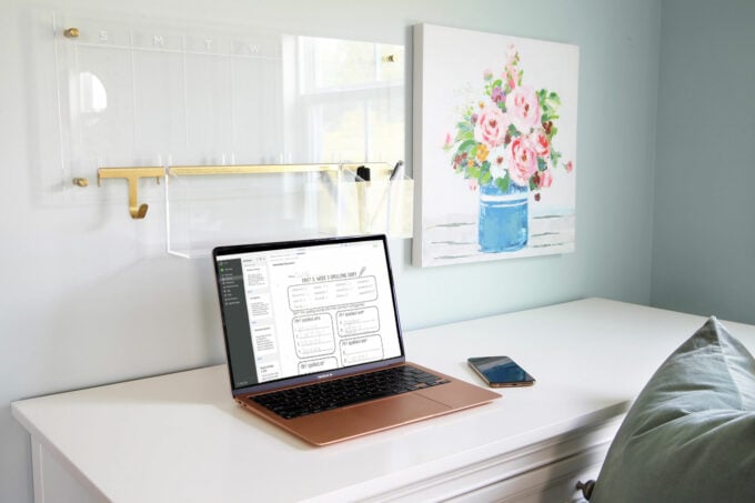 Computer sitting on a white desk with a with document in Evernote on the screen