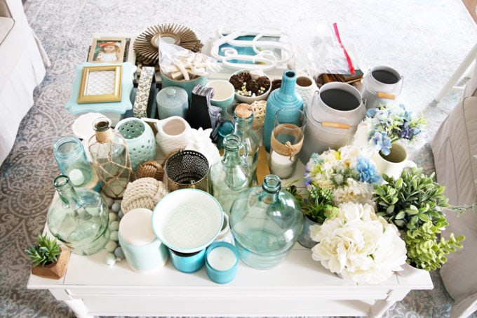 It can be a challenge to know how to decorate shelves, but this foolproof formula will teach you how to style shelves beautifully in no time! | #shelfie #shelfstyling #styledshelves #bookshelfstyling #livingroom #livingroomdecor #summerdecor #vignette Coffee Table Holding Tons of Decor in an Aqua, White, and Neutral Color Scheme
