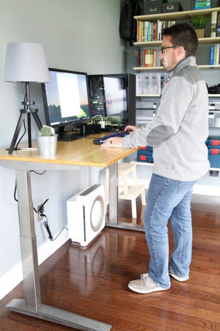 Man standing at motorized standing desk working on a desktop computer