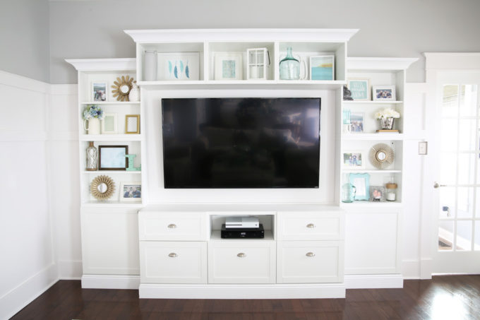 It can be a challenge to know how to decorate shelves, but this foolproof formula will teach you how to style shelves beautifully in no time! | #shelfie #shelfstyling #styledshelves #bookshelfstyling #livingroom #livingroomdecor #summerdecor #vignette Adding Tall Decorative Objects to the Ends of Shelves for Shelf Styling on a White Entertainment Unit in the Living Room