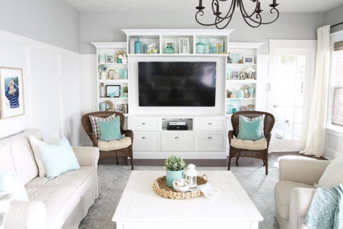 It can be a challenge to know how to decorate shelves, but this foolproof formula will teach you how to style shelves beautifully in no time! | #shelfie #shelfstyling #styledshelves #bookshelfstyling #livingroom #livingroomdecor #summerdecor #vignette White, Neutral, and Aqua Living Room with a Large Entertainment Unit that Has Beautifully Styled and Decorated Shelves