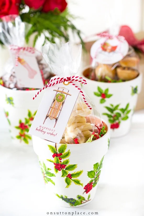 A painted flower pot filled with bagged baked goods and holiday tags, showcasing beautifully unique gift wrapping ideas perfect for handmade treats.