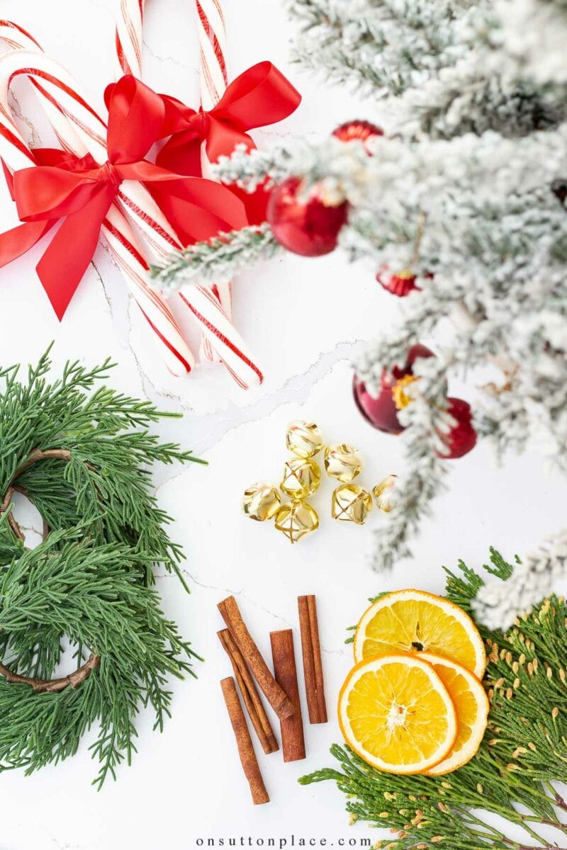 A set of candy canes, bells, and wreathes on a marble floor in front of a Christmas tree.