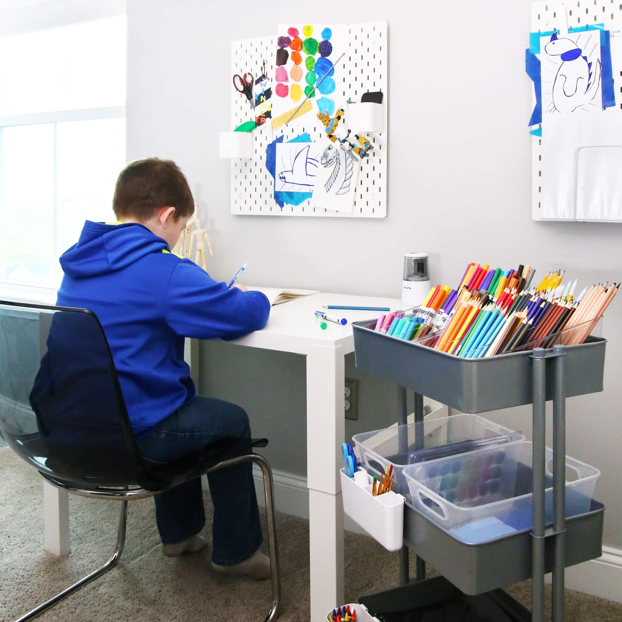 Boy working at a desk with an organized art cart for back to school
