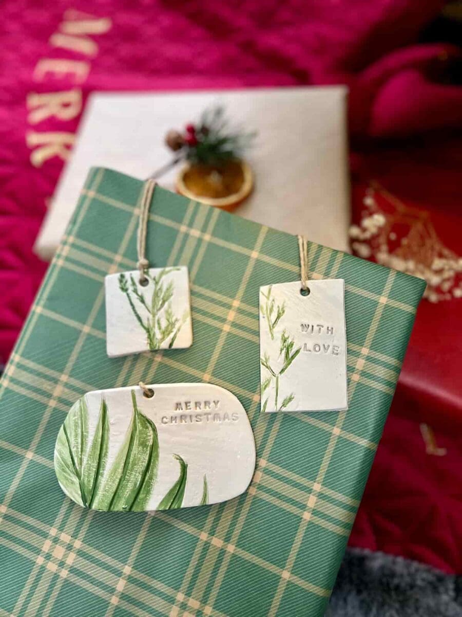 A green plaid wrapped package with DIY clay tags that say Merry Christmas and With Love.